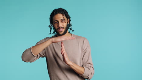 Assertive-man-asking-for-timeout,-doing-hand-gestures,-studio-background