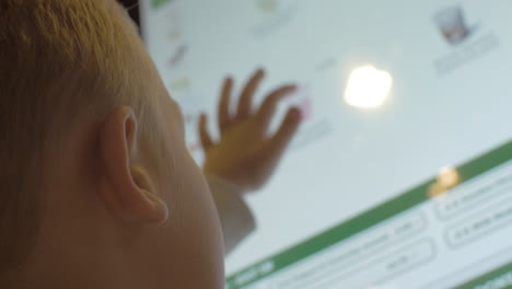 Close-up-back-view-of-small-blond-boy-choosing-meals-in-fast-food-restaurant-on-touch-screen