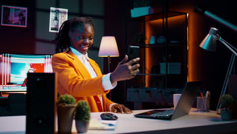 Young-woman-waving-at-phone-videocall-with-tutor-and-classmates