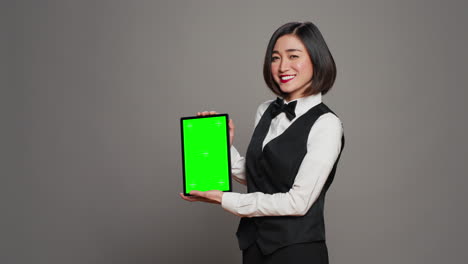 Woman-concierge-presenting-greenscreen-display-on-tablet