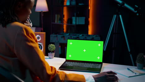 Junge-Frau-Benutzt-Laptop-Mit-Isoliertem-Greenscreen-Display-In-Ihrem-Heimbüro