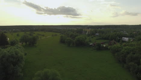 View-of-forest-lake-and-country-houses-against-blue-sky-with-sun-and-clouds-in-sunset-at-summer-Russia