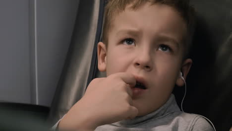 Boy-with-earphones-watching-TV-in-train