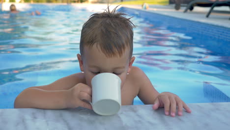 Niño-Pequeño-Bebiendo-Agua-En-La-Piscina