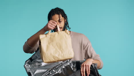 Courier-getting-meal-out-of-food-backpack,-isolated-over-blue-studio-background