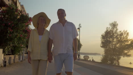Senior-couple-walking-on-sea-front-at-sunset