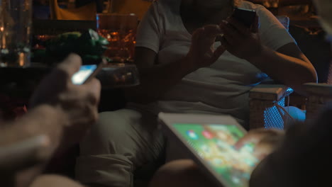 Three-people-using-their-phones-and-tablet-in-cafe