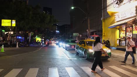 Personas-Que-Cruzan-Un-Carril-Peatonal-En-Una-Concurrida-Calle-De-Esquina-Cerca-De-La-Intersección-De-Asok-Y-Petchaburi,-Donde-Los-Vehículos-Se-Turnan-Para-Girar-A-La-Izquierda-Hacia-Ratchadaphisek-En-Bangkok