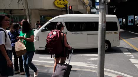 A-female-Jaywalker-with-a-green-shirt-crosses-the-pedestrian-lane-while-the-light-is-red-as-others-wait-for-the-light-to-turn-green,-Sukhumvit-24,-Bangkok,-Thailand