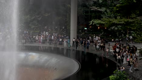 Jewel-indoor-waterfall-at-changi-airport-in-Singapore,-with-tourists-admiring-and-taking-pictures