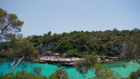 Mallorca:-Beach-Side-View-Of-Resort-In-Cala-Liombards-On-Majorca-Island,-Spain,-Europe-|-Turquoise-Ocean-with-Beach-Crowd
