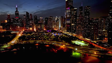 Aerial-tracking-shot-of-illuminated-parks-and-the-high-rise,-colorful-fall-dusk-in-Chicago