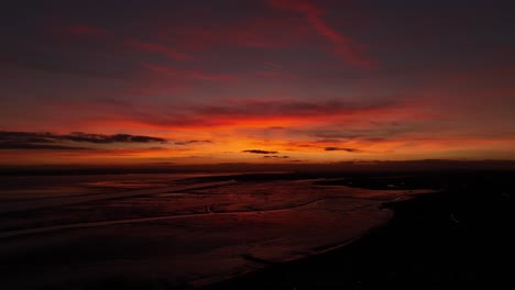 Der-Sonnenuntergang-Am-Strand-Von-Chalkwell,-Großbritannien,-Dreht-Sich-Von-Links-Nach-Rechts-Und-Zeigt-Einen-Epischen-Orangefarbenen,-Rostigen-Himmel-Und-Nassen-Sand