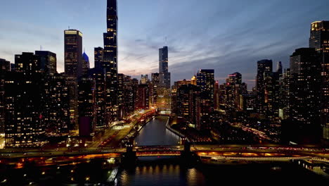 Aerial-view-following-the-Chicago-Riverwalk-in-middle-of-skyscrapers,-fall-dusk-in-USA