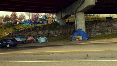 Tents-of-homeless-people-set-up-right-near-major-roadway-and-under-a-bridge-in-Portland,-Maine