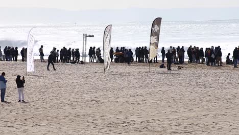 Onlookers-watch-professional-surfers-riding-large-crashing-waves-on-sunny-day