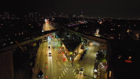 Static-drone-shot-of-elevated-railway-crossing-above-the-illuminated-streets-of-Wrigleyville,-Chicago