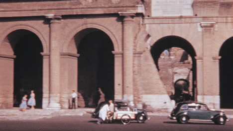 Vendedor-Ambulante-Empuja-Su-Carrito-De-Comida-Frente-Al-Coliseo-De-Roma-En-Los-Años-1960