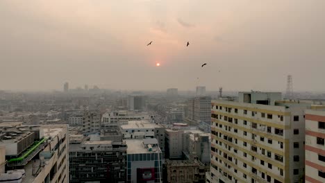 Aerial-drone-footage-over-skyline-of-Karachi-along-the-MA-Jinnah-road,-Karachi,-Pakistan-with-sun-setting-in-the-background