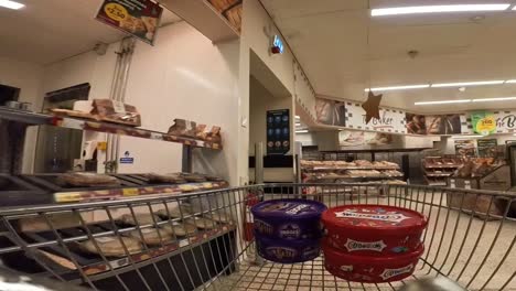 Shopping-cart-POV-around-supermarket-aisle-with-Christmas-grocery-stock-on-shelves-timelapse