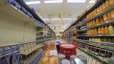 POV-supermarket-shopping-cart-walking-down-drinks-grocery-products-aisle