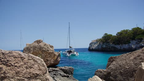 Mallorca:-Strandseitenansicht-Des-Resorts-In-Cala-Liombards-Auf-Der-Insel-Mallorca,-Spanien,-Europa-|-Boot-In-Der-Nähe-Tosender-Wellen