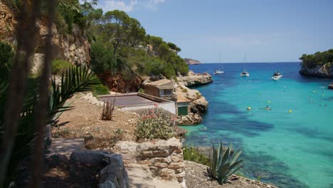 Mallorca:-Strandseitenansicht-Des-Resorts-In-Cala-Liombards-Auf-Der-Insel-Mallorca,-Spanien,-Europa-|-Häuser-In-Der-Nähe-Eines-überfüllten-Strandes