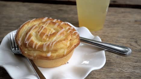 Honey-glazed-roll-on-a-small-porcelain-plate-with-knife-and-fork-on-the-side