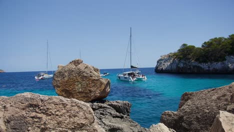 Mallorca:-Strandseitenansicht-Des-Resorts-In-Cala-Liombards-Auf-Der-Insel-Mallorca,-Spanien,-Europa-|-Drei-Schwimmende-Boote