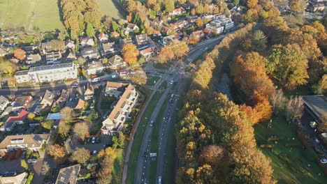 Aerial-of-a-busy-road-running-through-a-rustic-small-town-on-a-sunny-autumn-day