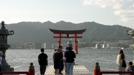 Besucher-Stehen-Schlange,-Um-Ein-Foto-Der-Schwimmenden-Jinja-Otorii-Im-Hintergrund-Am-Itsukushima-Schrein-Zu-Machen