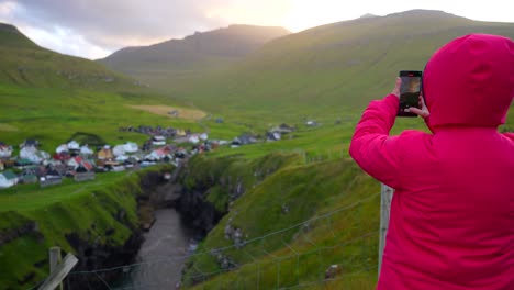 Female-tourist-taking-sunset-photos-of-Gjov-in-Faroe-Islands-for-social-media