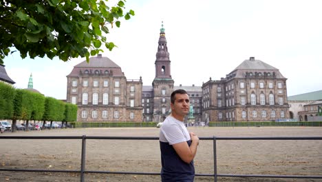Static-shot-of-male-tourist-in-front-of-Christiansborg-Palace,-Copenhaguen