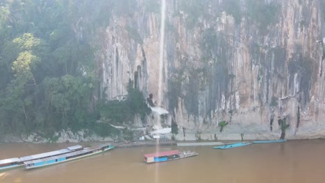 Luftaufnahme-Der-Klippen,-Die-Zu-Den-Pak-Ou-Höhlen-Am-Mekong-Fluss-In-Luang-Prabang-Führen,-An-Einem-Sonnigen-Tag-Mit-Blendenfleck