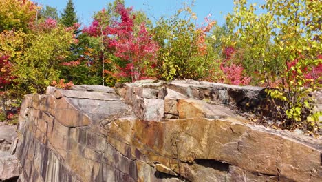 Die-Luftaufnahme-Zeigt-Sanft-Eine-Felswand-Aus-Granit-Und-Die-Wundervollen-Farben-Der-Bäume-Während-Des-Saisonalen-Wechsels-Im-Herbst