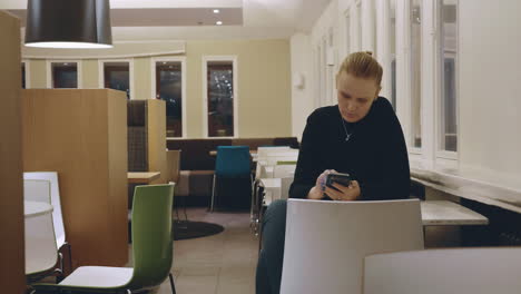 Blonde-passing-time-with-cellphone-in-cafe