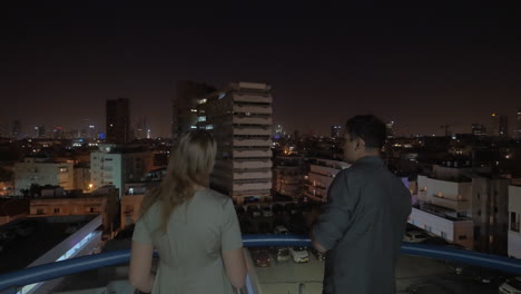 Man-and-woman-looking-at-night-Tel-Aviv-from-the-hotel-roof-Israel