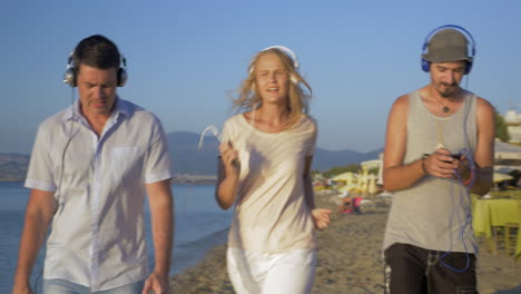 Three-friends-walking-with-music-on-the-beach