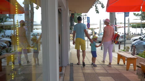 Familia-De-Tres-Personas-Saliendo-De-La-Tienda-Y-Caminando-Por-La-Calle