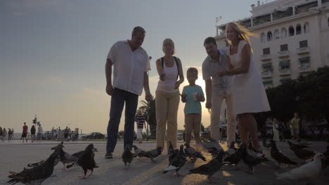 Family-feeding-pigeons-in-the-street-at-sunset