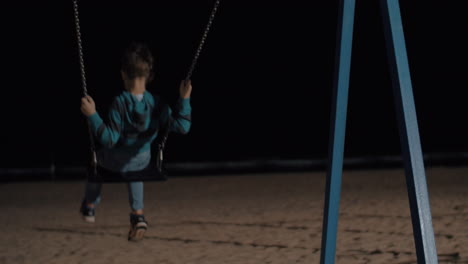 Child-swinging-on-the-beach-at-night