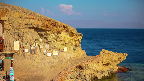 Time-lapse-of-people-walking-in-front-of-the-blue-hole-memorial,-sunset-in-Dahab,-Egypt