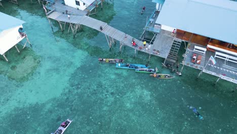 Overhead-Shot-Of-Bajau-Laut-Community,-Kayaks-Near-Wooden-Pier-In-Mabul-Island-At-Sunset,-Sabah,-Malaysia