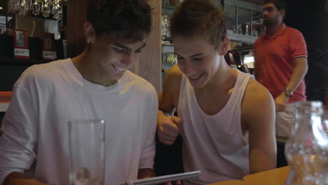 Two-teenagers-with-pad-in-cafeteria