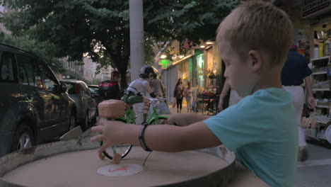 Kind-Spielt-Mit-Spielzeugfahrradfahrer-Auf-Der-Straße