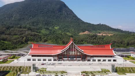 Aerial-View-Of-Luang-Prabang-Railway-Station-With-Forested-Mountain-In-Background