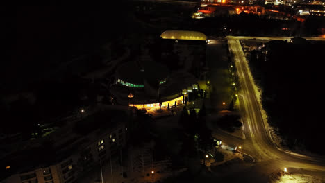 Aerial-tilt-shot-in-front-of-a-the-Tropiclandia-waterpark,-night-in-Vaasa,-Finland