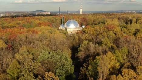 Aerial-shot-of-moving-towards-Silesian-Planetarium-in-the-middle-of-Park-in-Chorzow,-Poland