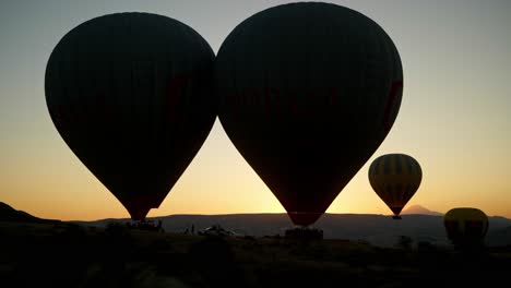 Silhouetten-Von-Heißluftballons-Starten-Am-Frühen-Morgen-Bei-Sonnenaufgang