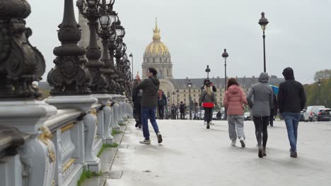 Menschen-überqueren-Die-Brücke-Pont-Alexandre-III-Mit-Den-Invaliden-Im-Hintergrund